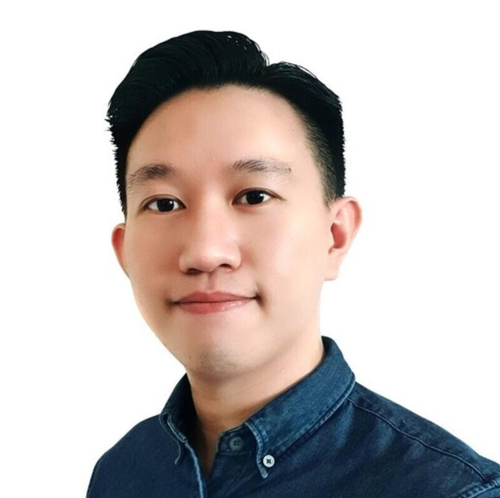 Young man wearing denim shirt facing camera in close-up headshot with white background
